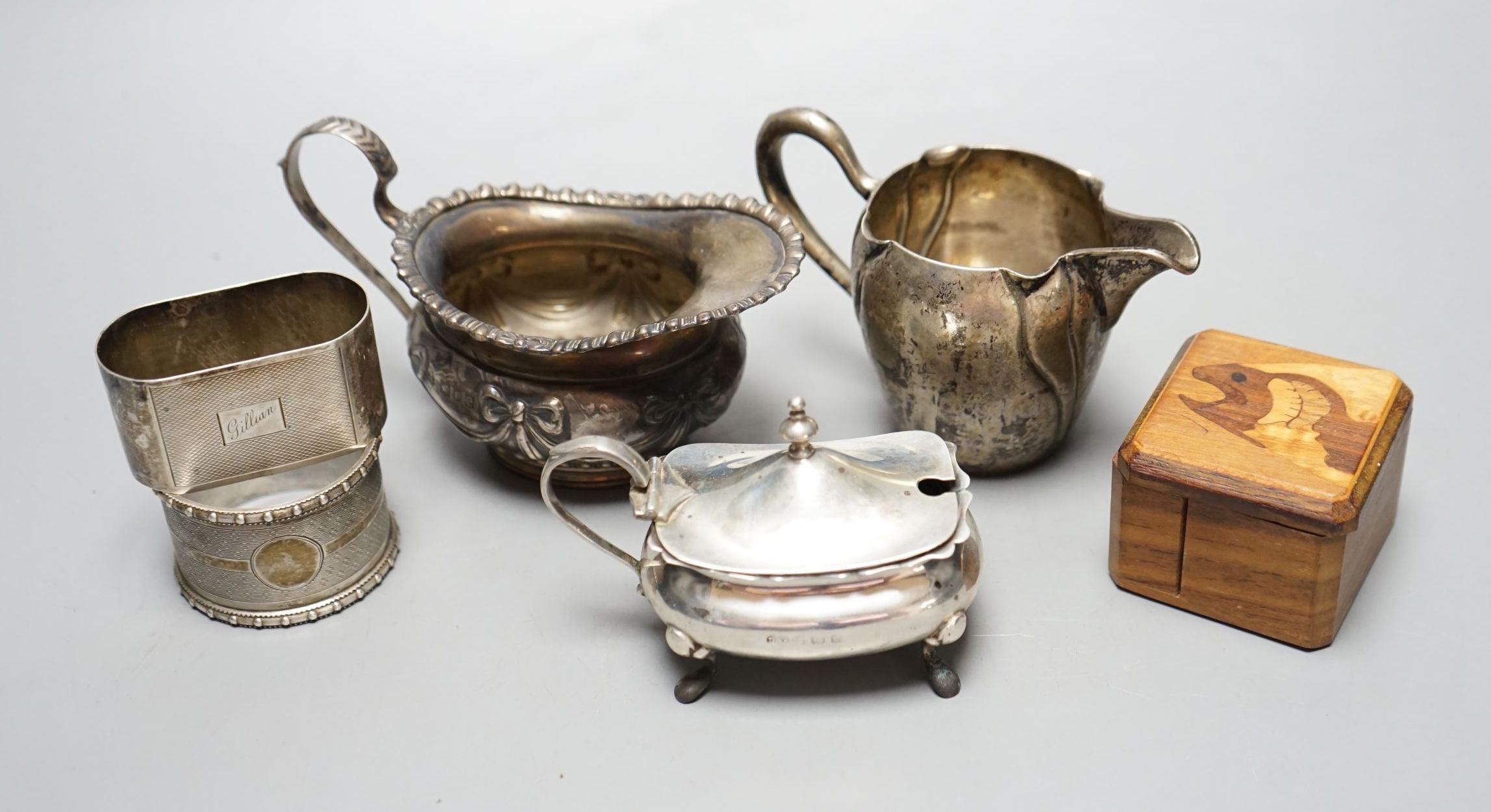 A late Victorian silver cream jug, London, 1900, a German 800 cream jug, a silver mustard pot, two silver napkin rings, a silver lid and a wooden box